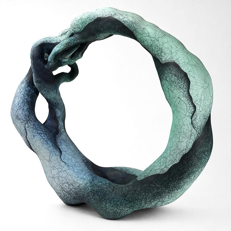 A contemporary sculpture featuring an abstract circular form with smooth, flowing lines and a gradient of colors ranging from dark to light blue.